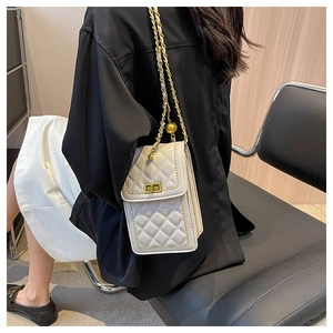 Quilted cream shoulder bag with golden chain and ball charm shown on a model outfit