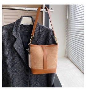 Detail of a brown patchwork bucket bag featuring contrast textures and gold hardware