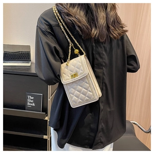 Detail view of cream quilted mini square bag with golden chain and twist lock on model