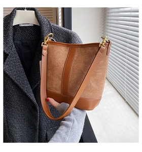 Detail of retro caramel bucket bag showing smooth leather stitching and gold metal hooks