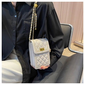Close-up of white quilted crossbody phone bag with gold chain strap and turn-lock