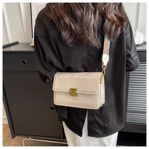 Détail du sac bandoulière en cuir crème avec fermoir doré et sangle à motifs colorés