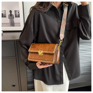 Détail du sac bandoulière vintage marron avec surpiqûres et bandoulière jacquard