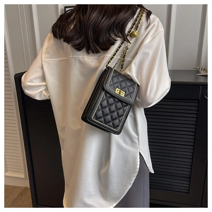 Detail of black quilted crossbody bag featuring gold chain strap and bead accents