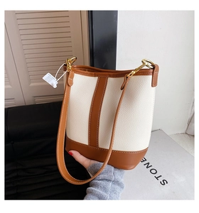 Detail of contrast stitch bucket bag with cream pebbled leather and brown trim