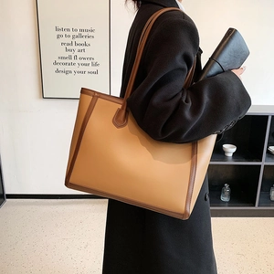 Large capacity khaki and brown contrast tote bag worn by a model in a modern office interior