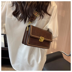 Détail du sac bandoulière marron rétro avec clous dorés et bandoulière tissée