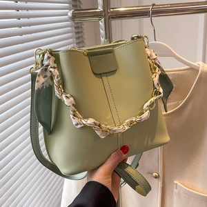 Elegant light green bucket bag with gold chain strap and floral silk scarf detail