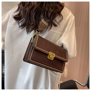Détail d'un sac bandoulière vintage marron avec rivets dorés et sangle colorée