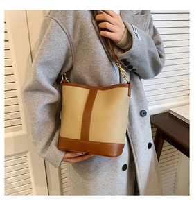 Chic beige and brown patchwork bucket bag shown on a model wearing a grey coat