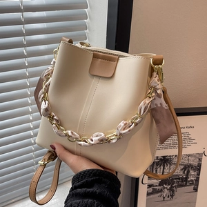Elegant cream bucket bag with silk scarf gold chain handle and brown leather shoulder strap