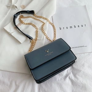 Morandi blue crossbody chain bag with golden deer logo on white blazer background