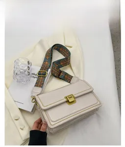 Détail d'un sac bandoulière blanc carré avec une sangle colorée style ethnique