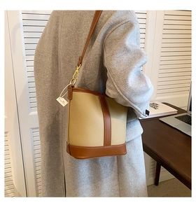 Detail of contrast stitching and beige lychee leather on a chic bucket shoulder bag