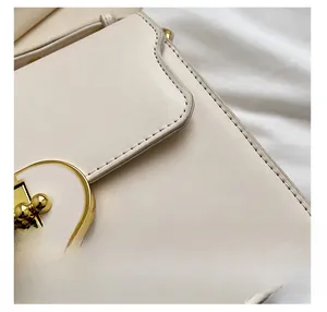 Détail du sac en cuir blanc crème avec boucle ronde dorée et coutures de haute qualité