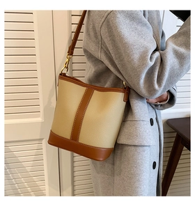 Close-up of beige lychee grain leather bucket bag with brown trim and gold hardware