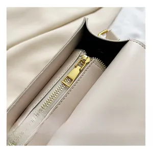 Détail d'une fermeture éclair dorée lisse sur un sac carré en cuir blanc crème élégant