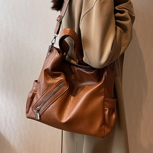 Grand sac cabas en cuir PU marron avec large bandoulière porté par une femme en manteau