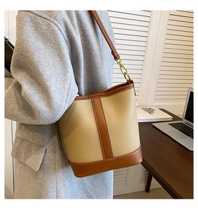 Detail of two-tone bucket bag featuring beige litchi grain and brown smooth leather