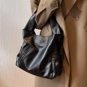 Grand sac cabas en cuir PU noir avec bandoulière large porté sur un trench-coat