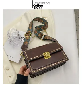 Détail du sac bandoulière vintage marron avec sangle tissée et boucle dorée chic