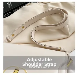 Détail de la bandoulière réglable avec boucle dorée sur un sac à main beige en cuir