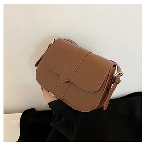 Detailaufnahme braune Leder Satteltasche mit vertikalen Streifen und goldenen Schnallen