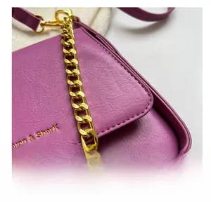 Close-up of purple litchi grain faux leather handbag with fine stitching and gold chain