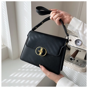 Sac à main en cuir noir mat avec fermoir rotatif ovale doré et une forme rectangulaire élégante