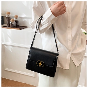 Détail d'un sac bandoulière chic en cuir noir avec boucle en métal doré sur le rabat avant