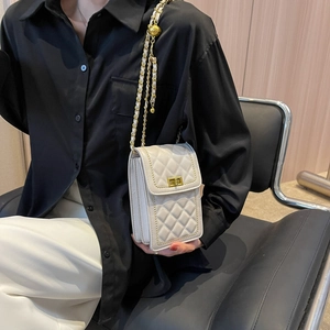 Chic white quilted chain bag with gold rotary lock worn by model on black shirt