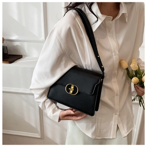 Détail du sac bandoulière en cuir noir minimaliste avec un fermoir doré en métal