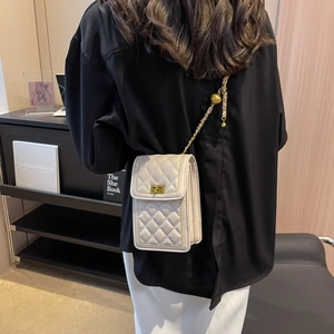 Quilted beige crossbody small square bag with gold chain and ball detail worn by model