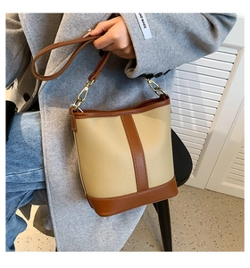 Detail of minimalist beige and brown bucket bag with lychee grain leather texture