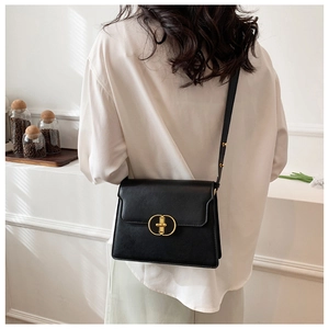 Détail du sac à bandoulière noir mat avec un fermoir métallique circulaire doré