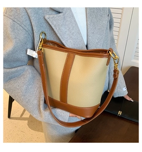 Detail of contrast stitching and bicolor leather textures on a fashion bucket bag
