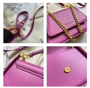 Detail of purple lychee textured handbag featuring golden chain and Muon & Shark logo
