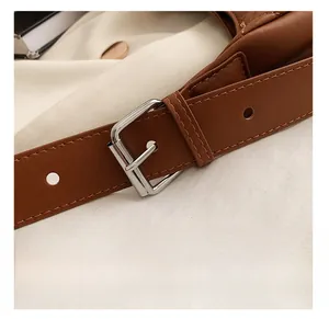 Detail of brown leather shoulder strap with silver buckle and fine stitching