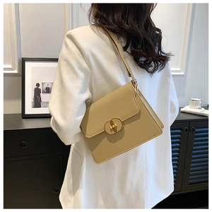 Détail d'un sac bandoulière carré beige doté d'un fermoir ovale doré sur le rabat