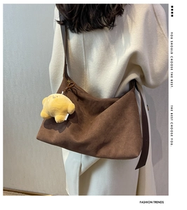 Brown frosted leather tote bag with star plush charm on model in white wool coat