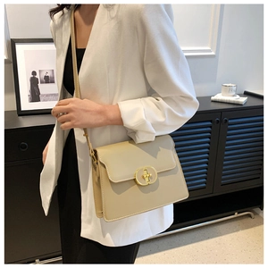 Détail d'un sac bandoulière crème avec fermoir ovale doré et fine bandoulière en cuir