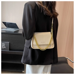 Chic cream crossbody bag with golden chain strap styled on a black blazer