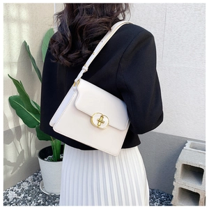 Détail d'un petit sac bandoulière blanc crème en cuir avec boucle dorée porté par un mannequin