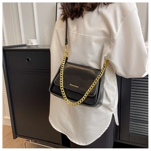 Detail of black textured leather bag with gold chain strap and brand lettering