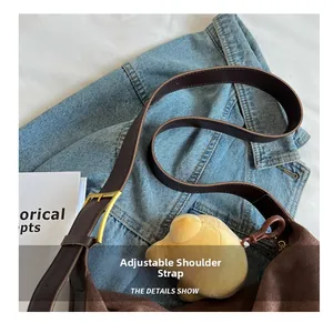 Detail of adjustable leather strap and golden metal buckle on a brown suede tote bag