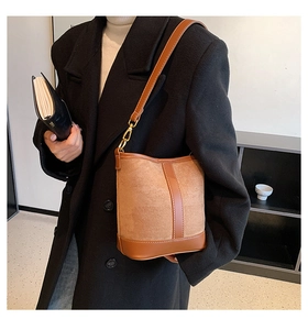 On-body shot of a brown bucket bag in suede and leather mix with gold metal hooks