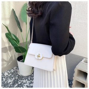 Détail du petit sac bandoulière crème avec fermoir rotatif doré et fine lanière cuir