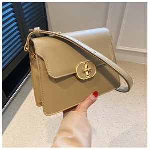 Détail d'un sac bandoulière carré beige avec fermoir ovale en métal doré très élégant