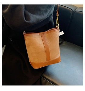 Detail of brown contrast bucket bag featuring suede and smooth leather with gold hardware