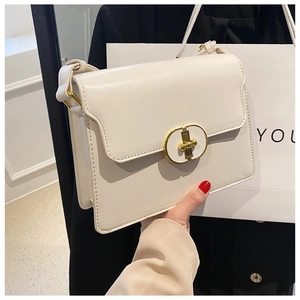 Gros plan d'un sac bandoulière blanc rectangulaire avec fermoir tournant doré et coutures fines